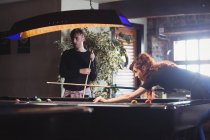 Молодая счастливая пара играет в бильярд в баре — стоковое фото