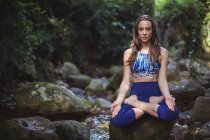 Mujer meditando en posición de loto en el bosque - foto de stock