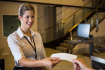 Personal femenino que da billete a pasajeros en la terminal del aeropuerto - foto de stock