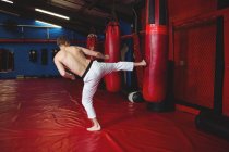 Каратист, практикующий кикбоксинг в фитнес-студии — стоковое фото