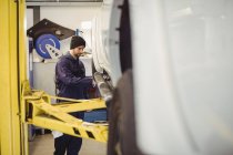 Mecânico examinando um carro na garagem de reparação — Fotografia de Stock