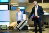 Бізнесмен, який витягує свій багаж з зони багажу в терміналі аеропорту — стокове фото