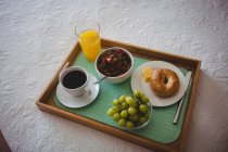 Primer plano de la bandeja de desayuno en la cama en el dormitorio en casa - foto de stock
