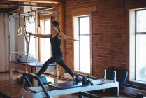 Mulher praticando pilates em reformador no estúdio de fitness — Fotografia de Stock