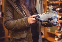Primer plano de la mujer que selecciona el zapato en una tienda - foto de stock