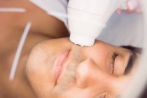 Uomo ottenere massaggio facciale per il trattamento cosmetico in clinica — Foto stock