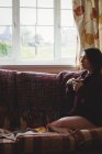 Donna premurosa seduta e con una tazza di caffè in mano a casa — Foto stock