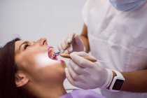 Dentista examinando os dentes do paciente feminino na clínica — Fotografia de Stock
