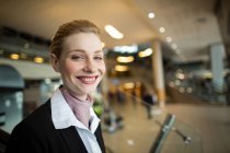 Retrato del asistente de facturación sonriente de la aerolínea en el mostrador en la terminal del aeropuerto - foto de stock