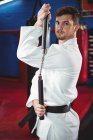 Retrato del jugador de karate practicando con nunchaku en el gimnasio - foto de stock