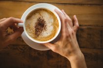 Mãos de mulher segurando xícara de café no café — Fotografia de Stock