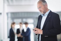 Бизнесмен использует мобильный телефон в офисном здании — стоковое фото
