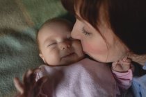 Мати цілує дитину в спальні вдома, крупним планом — стокове фото