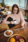 Женщина с помощью цифрового планшета, держа чашку кофе дома — стоковое фото