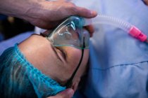 Руки лікаря розміщують кисневу маску на обличчі вагітної жінки в операційній кімнаті — стокове фото