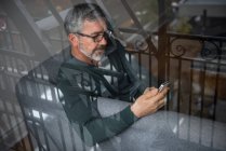 Человек, использующий мобильный телефон в гостиной дома — стоковое фото