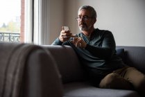 Людина, що використання мобільного телефону у вітальні на дому — стокове фото