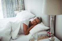Senior woman resting on bed in bedroom at home — Stock Photo