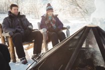 Skifahrerpaar sitzt am Lagerfeuer im Skigebiet — Stockfoto