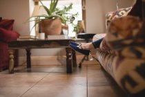 Gambe di ragazza seduta sul divano in soggiorno a casa — Foto stock