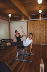 Trainer assisting mid adult woman while practicing pilates in fitness studio — Stock Photo