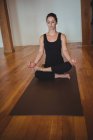 Woman meditating on yoga mat in fitness studio — Stock Photo
