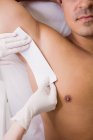 Крупный план врача по эпиляции мужской кожи пациента в клинике — стоковое фото