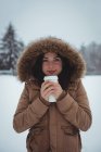 Портрет улыбающейся женщины в меховой куртке, пьющей кофе зимой — стоковое фото