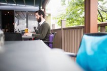 Человек с ноутбуком на террасе бара — стоковое фото