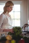 Schöne Frau wäscht Brokkoli unter der Spüle in der Küche zu Hause — Stockfoto