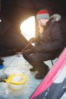 Ice fisherman fishing while sitting in tent — Stock Photo