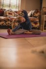 Fille effectuant yoga étirement exercice dans le salon à la maison — Photo de stock