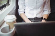 Средняя часть деловой женщины, использующей ноутбук во время путешествия — стоковое фото