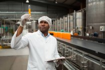 Travailleur masculin sérieux examinant le jus dans l'usine — Photo de stock