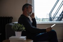 Hombre hablando por teléfono móvil en la sala de estar en casa - foto de stock