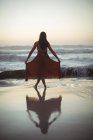 Вид ззаду жінки позує на пляжі в сутінках — стокове фото