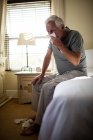 Старший использует салфетку, чтобы высморкаться в спальне дома — стоковое фото