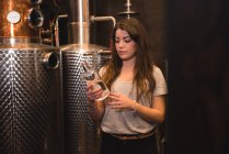 Frau untersucht eine Flasche Alkohol in Bierfabrik — Stockfoto