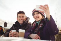 Happy skier couple clicking a selfie in ski resort — Stock Photo