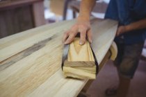 Close-up of man using sanding box on surfboard in workshop — Stock Photo