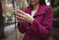 Обрізаний вид бізнес-леді, використовуючи телефон, стоячи на шляху — стокове фото