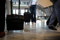 Pasajeros caminando con equipaje en la sala de espera en el aeropuerto - foto de stock
