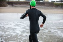Vista trasera del atleta corriendo hacia la playa - foto de stock