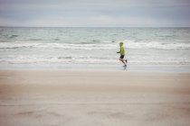 Вид сзади спортсмена, бегущего по пляжу — стоковое фото