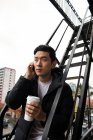 Hombre usando tableta digital mientras toma café en balcón - foto de stock