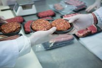Carniceros empacando carne picada en una bandeja de plástico en la fábrica de carne - foto de stock