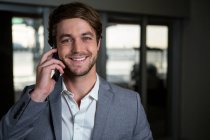 Portrait smiling businessman talking on his mobile phone in the airport terminal — Stock Photo