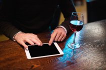 Empresário usando tablet digital com copo de vinho no balcão no bar — Fotografia de Stock