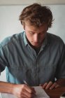 Uomo seduto alla scrivania a scrivere sul taccuino a casa — Foto stock