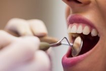 Gros plan du dentiste examinant une patiente avec des outils à la clinique dentaire — Photo de stock
